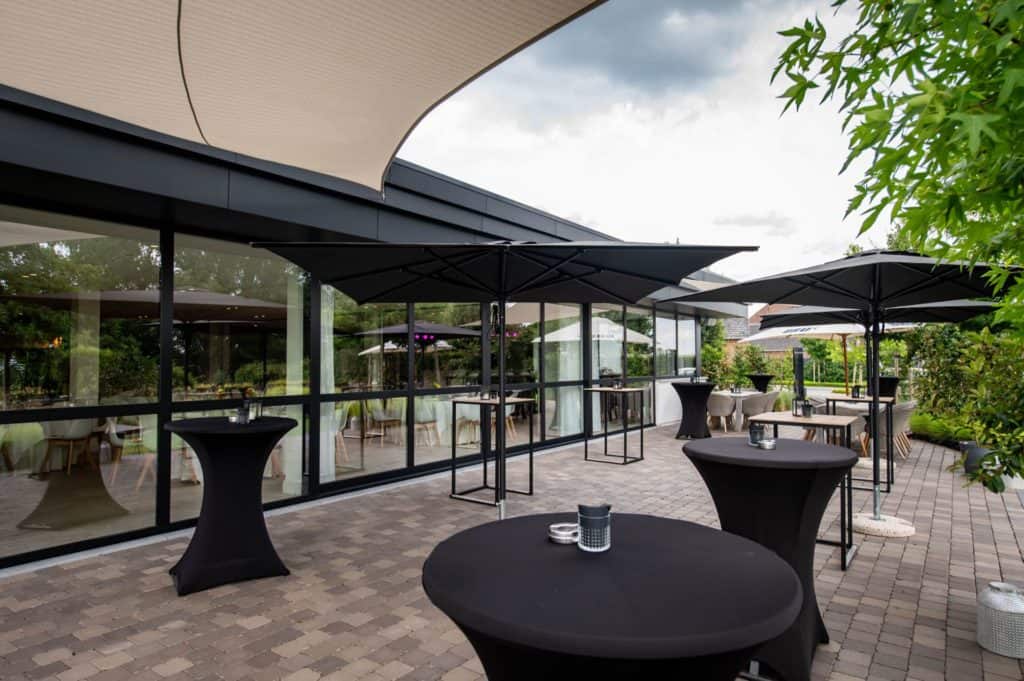 Een stenen terras met tafels en parasols.