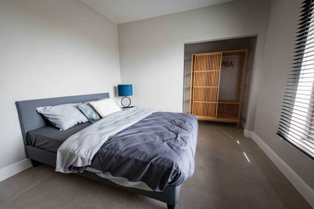 Een slaapkamer met een gezellige sfeer, voorzien van een comfortabel bed en een stijlvol dressoir.