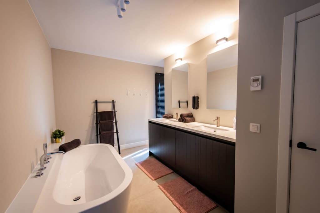Een badkamer met ligbad en wastafel, waardoor een serene sfeer ontstaat.