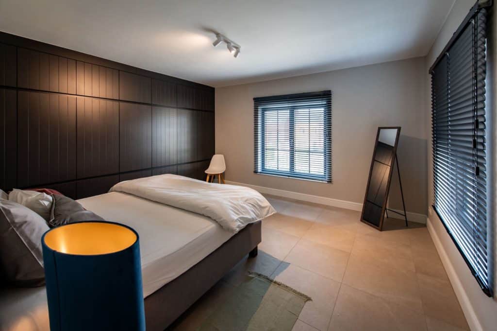 Een slaapkamer met een gezellige sfeer, voorzien van een comfortabel bed en een stijlvolle lamp.