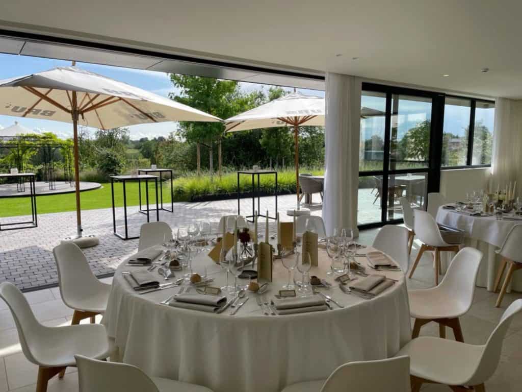 Een witte tafel met witte stoelen en parasols.