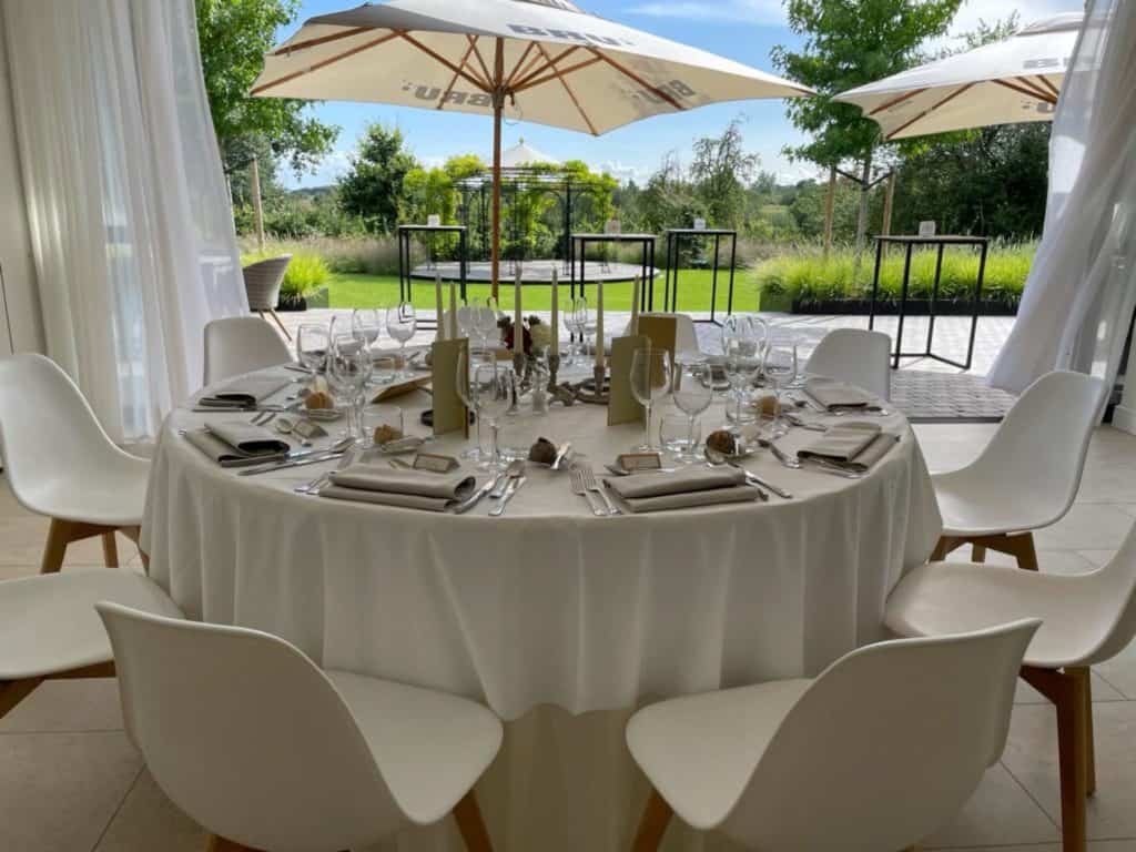 Een tafel gedekt met witte stoelen en parasols.