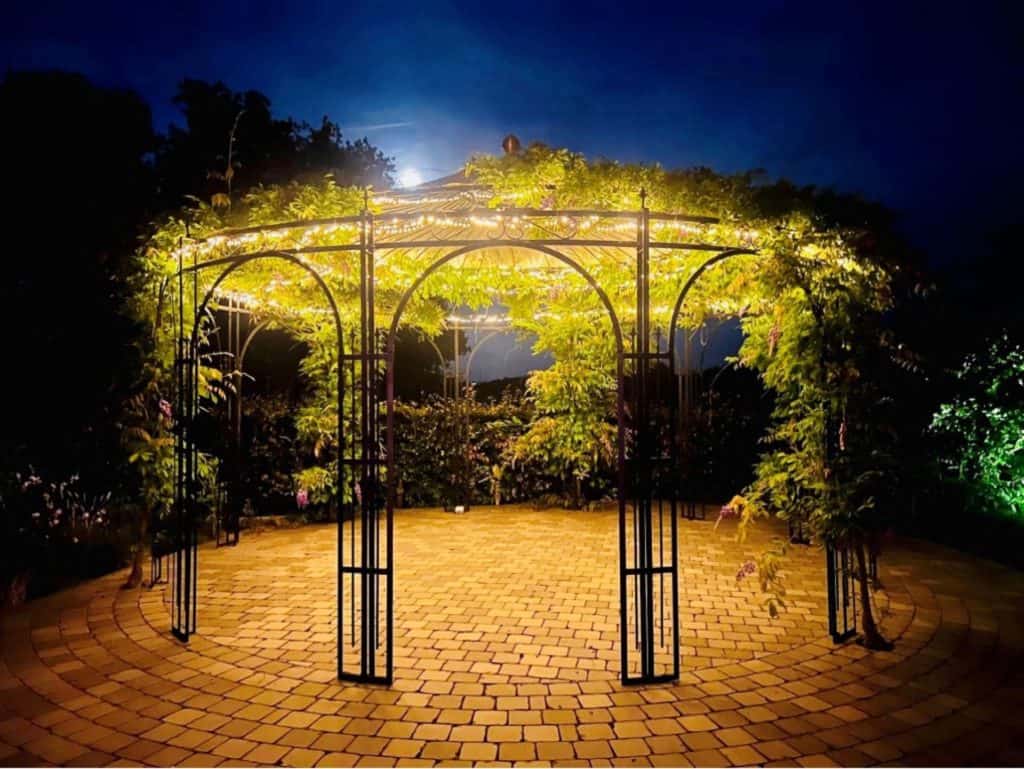Een prachtig verlicht tuinpaviljoen dat 's avonds een magische sfeer creëert in een tuin.